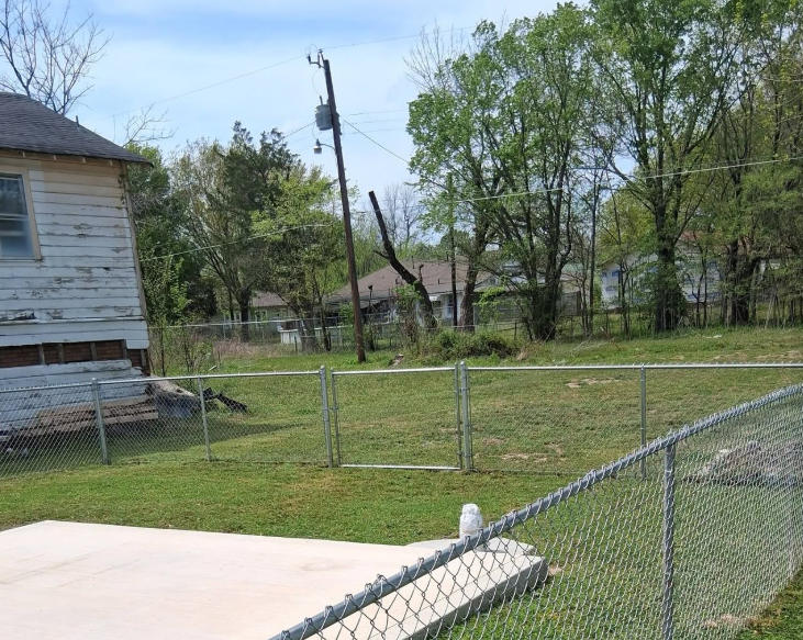 Fenced back lot mowed clean around a concrete patio slab