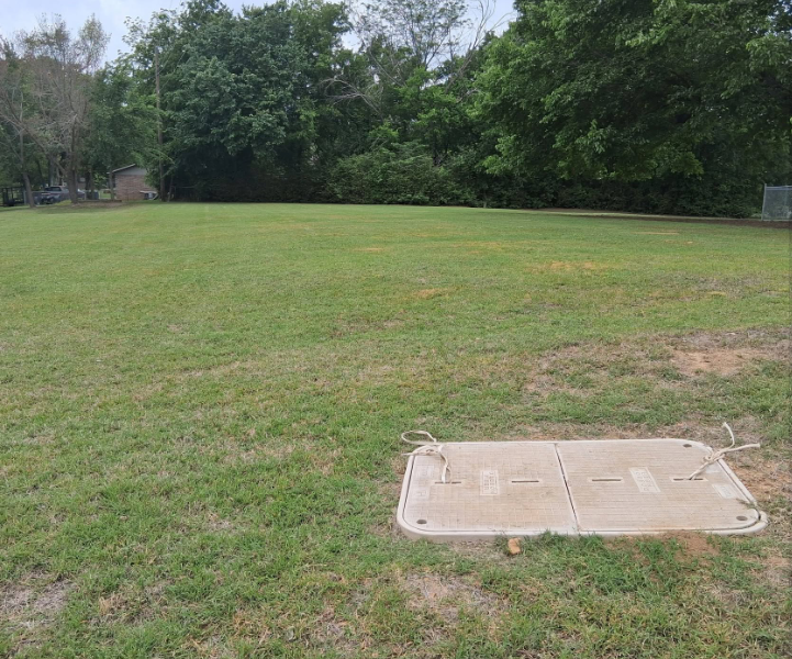 Utility lot mowed neatly around a concrete access cover