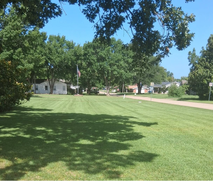 Freshly mowed and striped green lawn in front of a brick home in McAlester, Oklahoma