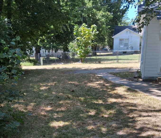 Dry uneven grass in a shaded side yard before service in McAlester, OK