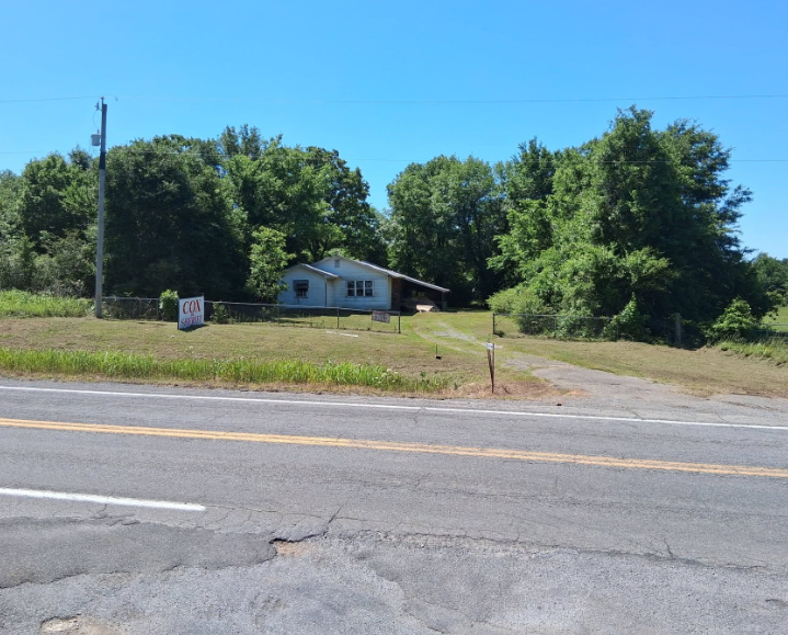 Roadside acreage mowed in front of a small house on a rural highway