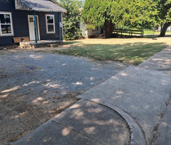 Edged sidewalk and cleared gravel drive beside a dark blue house