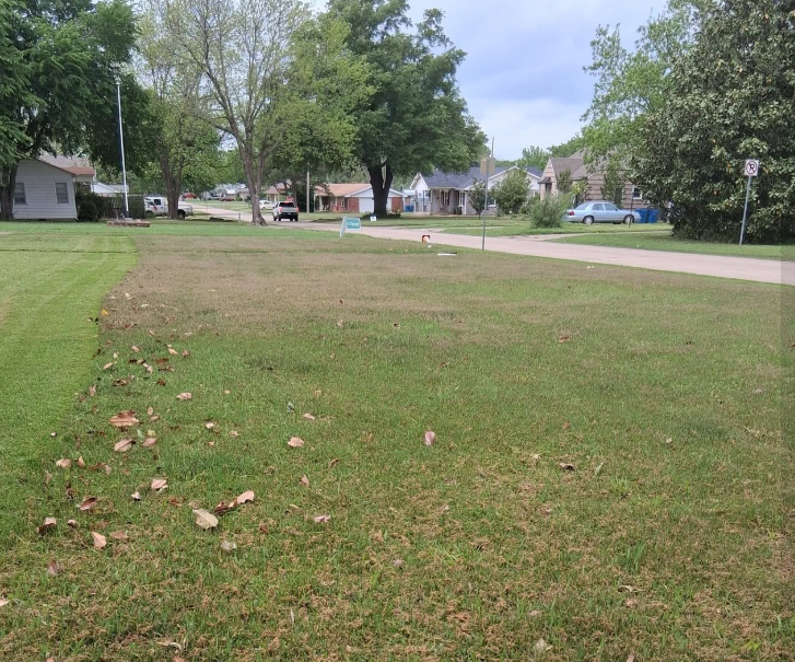 Wide neighborhood lot mowed and edged along the street in McAlester, OK