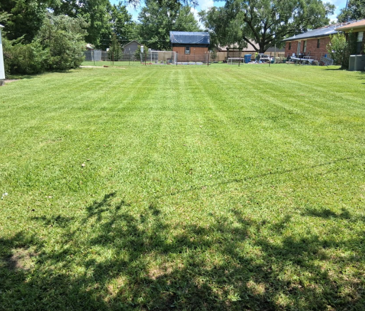 Wide back yard mowed in clean stripes behind a brick home