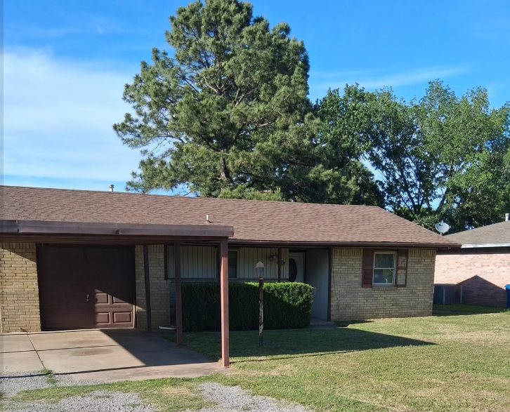 Brick home with a mowed front lawn and neatly trimmed hedges