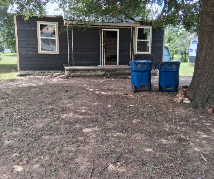 Bare shaded yard cleared of debris beside a dark sided house